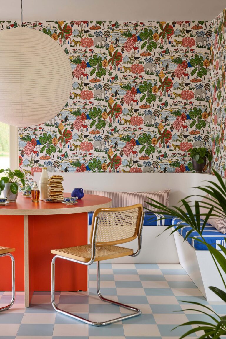 Cucina colorata con carta da parati a motivo naturalistico e isola arancione