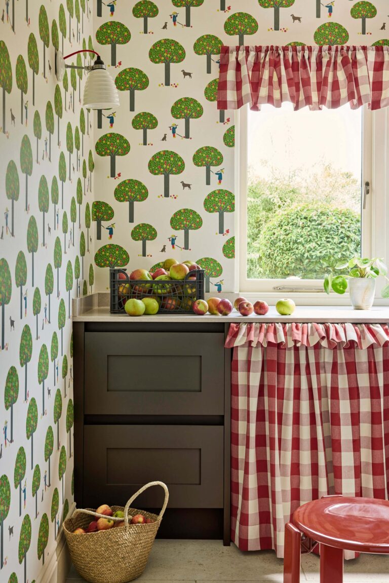 Cucina con carta da parati ad alberi verdi, mobili verde scuro e tendina a quadretti