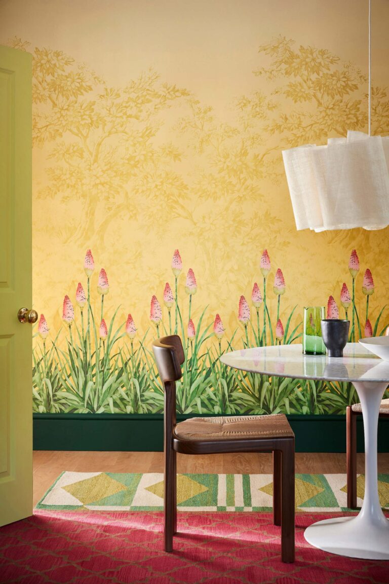 Ambiente con murale giallo a prato fiorito e tavolo tondo