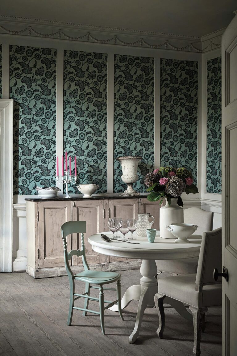 Sala da pranzo verde scuro con carta da parati a riquadri e credenza chiara