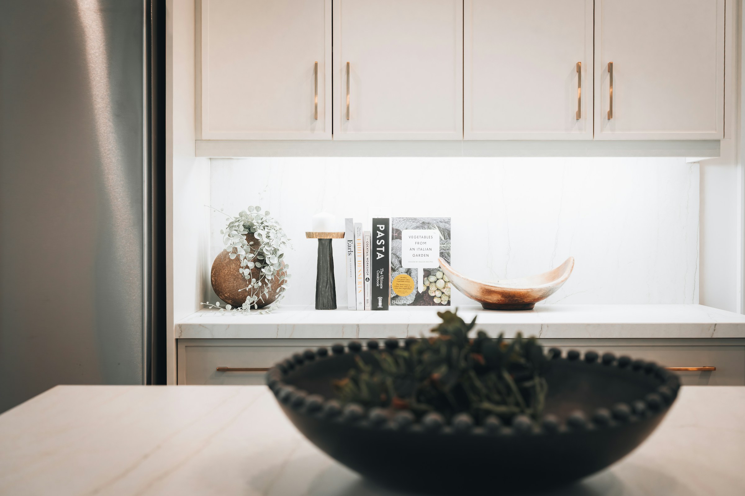 Piano di cucina con ante lisce e mensola con oggetti decorativi